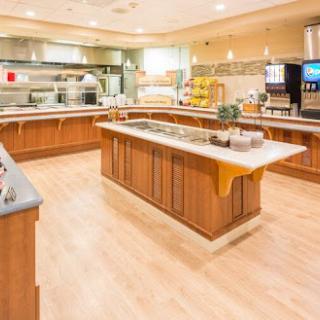 A spacious and modern kitchen buffet setup, featuring wooden cabinetry and various food stations.