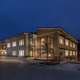 A modern two-story building illuminated at night, showcasing its architectural design with bright windows.