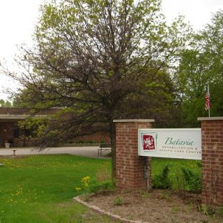 A welcoming entrance with a sign and greenery.
