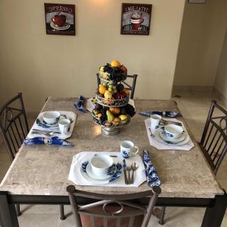 A neatly set dining table with a fruit centerpiece, ready for a meal in a cozy kitchen setting.