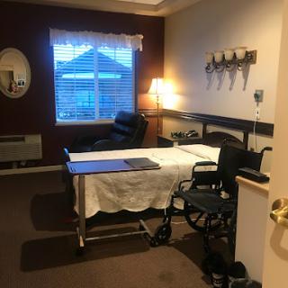 A cozy hospital room equipped for patient care with a bed, wheelchair, and soft lighting.