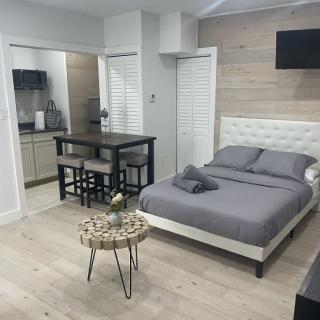 Modern studio apartment with a cozy bed, kitchenette, and minimalist decor.
