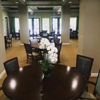 A spacious dining area with elegant tables, chairs, and a decorative orchid centerpiece.