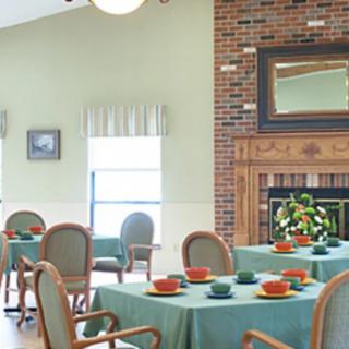 A cozy dining room with neatly arranged tables and a warm fireplace.