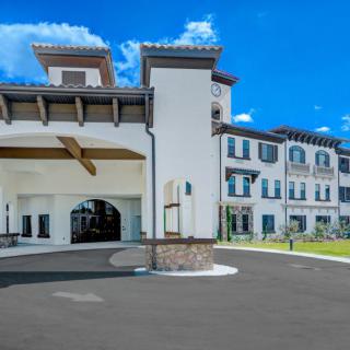 A modern multi-story building with a spacious entrance and clear blue sky.