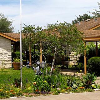 A suburban house with a garden and small trees in the front yard.