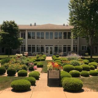 A beautifully landscaped garden leads to a large building under a clear sky.