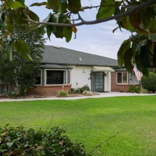 A suburban house with a well-maintained lawn and surrounding trees.