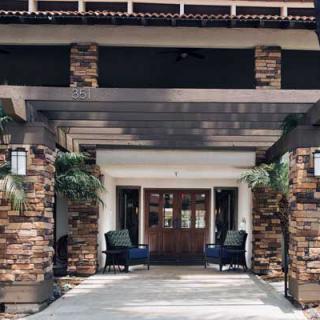 A welcoming building entrance with stone pillars and comfortable outdoor seating.