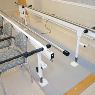 A set of parallel bars used for physical therapy and rehabilitation exercises in a therapy room.