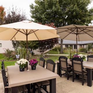 A cozy outdoor dining area featuring tables with umbrellas and flowering plants.