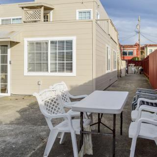 A patio area with white plastic chairs and a table next to a house.