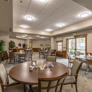 A spacious dining area with elegant tables and chairs, featuring warm lighting and tasteful decor.