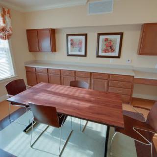 A light-filled dining room featuring a wooden table, chairs, cabinetry, and decorative artwork on the wall.