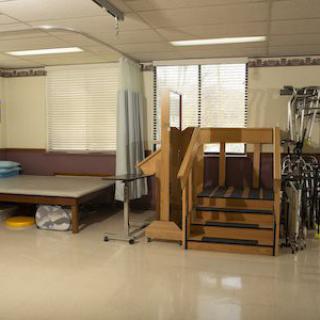 A physical therapy clinic with exercise equipment and a rehabilitation staircase.