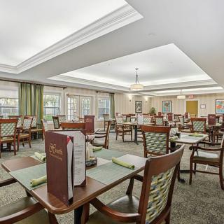 A spacious dining area with neatly arranged tables and chairs, menus placed on each table, and soft ambient lighting.