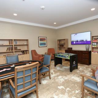 A cozy game room featuring a foosball table, various chairs, a television, and bookshelves with a carpeted floor.