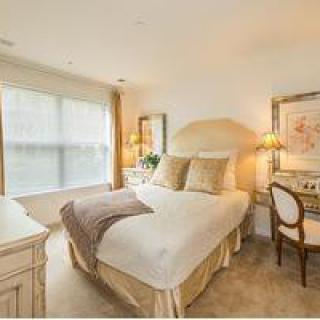 A cozy bedroom with neutral colors, featuring a comfortable bed, elegant decor, and ample natural light.