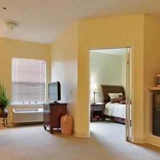 A cozy living room with a television, leading into a bedroom.