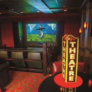 A cozy theater interior with rows of seating facing a screen displaying an animated scene.