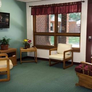 A cozy waiting room with chairs, plants, and a TV by the window.