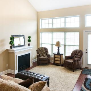 A cozy living room with a fireplace, large windows, and comfortable seating.