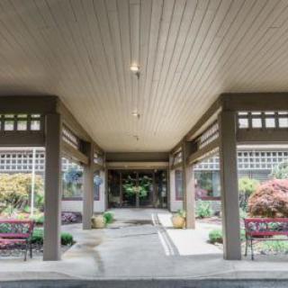 A covered walkway with columns surrounded by a landscaped garden.