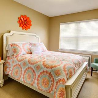 A cozy bedroom with colorful bedding and bright wall decor.