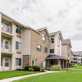A modern apartment building with a landscaped lawn and multiple balconies.