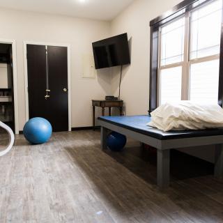 A physical therapy room equipped with an exercise ball and massage table.
