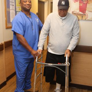 A nurse assists a patient using a walker in a rehabilitation setting.