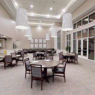 A modern and spacious dining area with round tables, comfortable chairs, and elegant lighting fixtures.