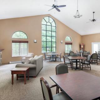 A spacious living area featuring large windows, tables, and comfortable seating.
