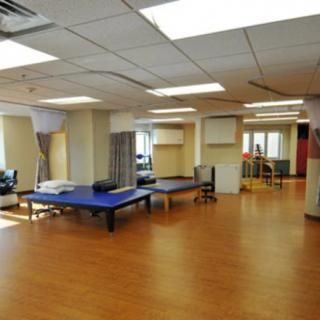 A spacious therapy room with treatment tables and exercise equipment.