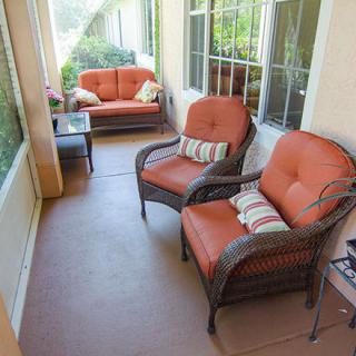 A cozy porch with wicker furniture and vibrant cushions, perfect for relaxing outdoors.