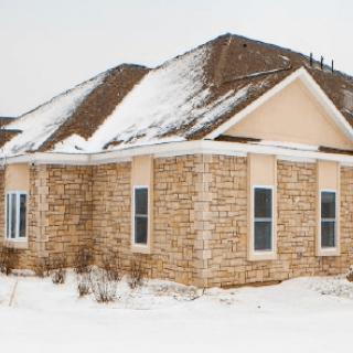 A brick house with a snow-covered roof during winter.