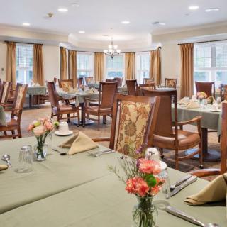 An elegant dining room with neatly arranged tables and chairs, decorated with flowers and napkins.