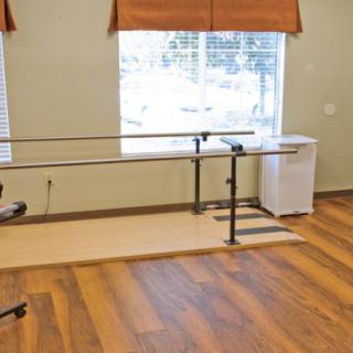 A rehabilitation room featuring parallel bars for physical therapy exercises.