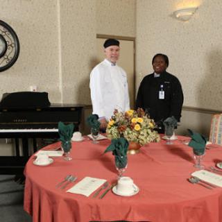 A well-set dining table with two staff members preparing for an event.