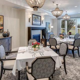 An elegantly decorated dining room with formal table settings and decorative chandeliers.