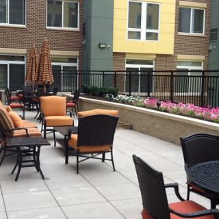 Modern patio area with outdoor seating and plants, set against an apartment building.