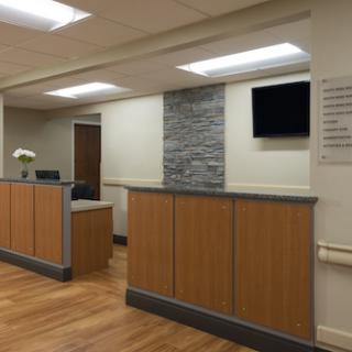 A modern healthcare reception area featuring wooden furnishings and bright lighting.