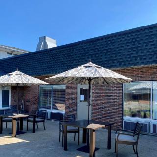 A cozy outdoor patio with tables and umbrellas against a brick building under a clear blue sky.