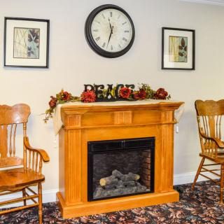 Cozy room with a wooden fireplace, clock, and two chairs.