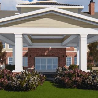 A building entrance featuring large columns and landscaped gardens.