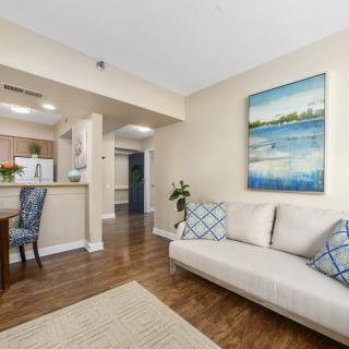 A cozy living room with an open layout, featuring a comfortable sofa, wall art, and a dining area connected to the kitchen.
