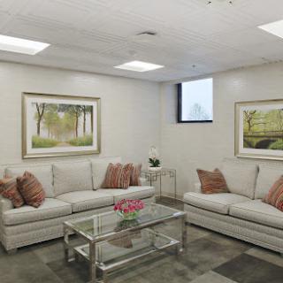 A cozy and elegantly designed living room featuring a comfortable white sofa, decorative pillows, and framed artworks on the walls.