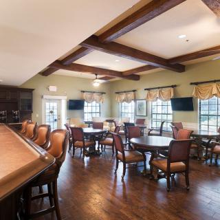 A cozy dining area with wooden floors, tables, and chairs arranged next to large windows.