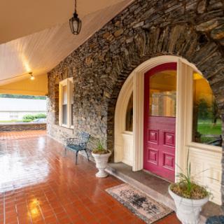 A charming entrance featuring a stone wall and a vibrant pink door, inviting you into the cozy home beyond.