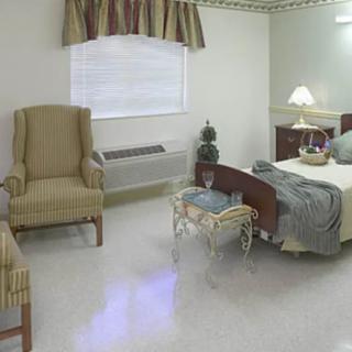 A cozy bedroom with a bed, armchair, and bedside lamp.